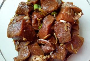 洗干净的牛肉放在玻璃器具中，加入切好的葱姜蒜。加入一勺料酒。再加入一勺生抽。戴上一次性手套用手轻轻按摩牛肉，再抓拌均匀，盖上盖子，放入冰箱腌制30分钟。