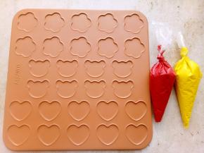 把混合好的马卡龙糊装入裱花袋里，红色和黄色做花形和心形马卡龙。