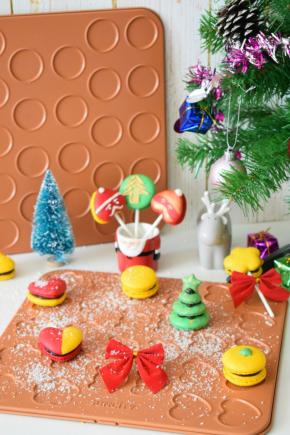 出炉后放凉，用白巧挤上圣诞的图案，食用金粉加一点点蛋清刷在图案上做装饰。然后在两片马卡龙中间挤上榛子巧克力酱再放上棒棒糖纸棒这样马卡龙棒棒糖就做好了。