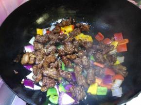 转大火迅速倒入羊肉丁，撒入少许孜然粒、烹入少许生抽快速翻炒均匀即可出锅