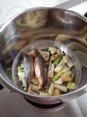 取高压锅，锅底铺上全部的葱姜蒜，上面放鱼