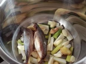 取高压锅，锅底铺上全部的葱姜蒜，上面放鱼