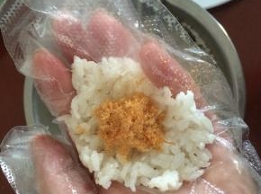 取一些拌均匀的米饭，压平整一些，放入适量肉松