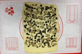 铺上三果，其中一边留2～3厘米左右不放三果，留做封边粘合。 核桃仁的大小不宜太大，太大了卷的不紧，我用的核桃仁大小是核桃的四分之一大小。