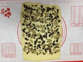 铺上三果，其中一边留2～3厘米左右不放三果，留做封边粘合。 核桃仁的大小不宜太大，太大了卷的不紧，我用的核桃仁大小是核桃的四分之一大小。