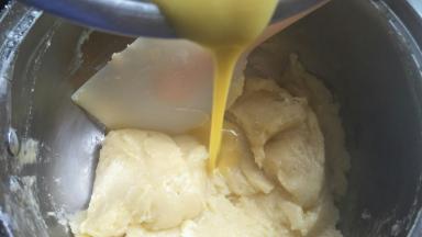 往烫熟的面粉中分次加入蛋液，至提起刮刀面糊呈倒三角。