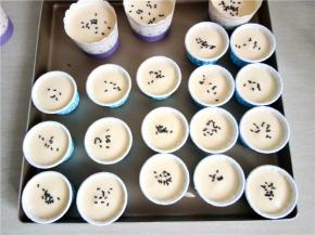 把拌好的蛋糕糊倒到裱花袋，挤入蛋糕杯中（7分满）表面撒上黑芝麻装饰。全部挤完后提起烤盘震两下，把大的气泡震出来！