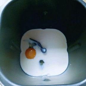 将牛奶倒入面包桶，再加入鸡蛋。