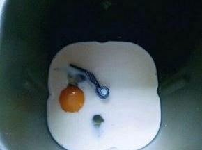 将牛奶倒入面包桶，再加入鸡蛋。