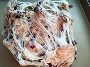 两手将雪花酥拉扯开、折叠，反复操作，使棉花糖包裹饼干、果脯和坚果，千丝万缕