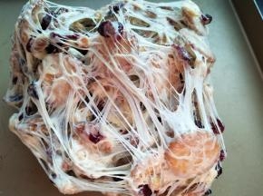 两手将雪花酥拉扯开、折叠，反复操作，使棉花糖包裹饼干、果脯和坚果，千丝万缕