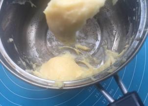 分次加入12-15克蛋液，拌匀至倒挂3-4厘米三角。把泡芙液装入裱花袋，裱花袋剪个0.3的小口