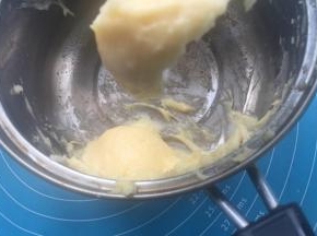 分次加入12-15克蛋液，拌匀至倒挂3-4厘米三角。把泡芙液装入裱花袋，裱花袋剪个0.3的小口