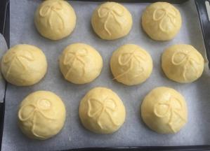 发酵到1.5-2倍的面团，涂稀释蛋黄液，挤上泡芙液蝴蝶结。
