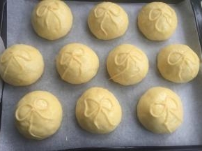 发酵到1.5-2倍的面团，涂稀释蛋黄液，挤上泡芙液蝴蝶结。