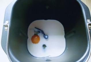 将牛奶倒入面包桶，再加入鸡蛋。