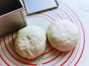 将面团从面包机中取出，分成2等份，揉圆，盖上保鲜膜松弛10分钟。