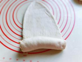 取一块面团用擀面杖擀长舌状，再卷起来，从上往下卷，依次做完。