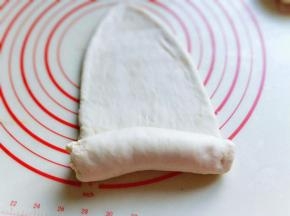 取一块面团用擀面杖擀长舌状，再卷起来，从上往下卷，依次做完。