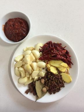 准备好所需的调料:蒜瓣剥皮稍微拍一下即可，生姜切片，干辣椒切成段，花椒，八角，香叶，郫县豆瓣酱，肉蔻！