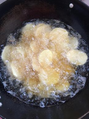 把沥干水分的土豆片，一片一片的放入锅中进行炸制！