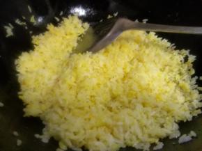 锅里留出的底油放入米饭，小火翻炒两分钟蒸发水分使米饭成一粒粒状，倒入蛋黄液，继续小火翻炒至蛋液与米饭粒融合在一起，成金黄色米饭