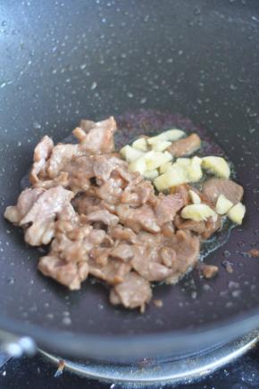锅里倒入油，放入肉片滑炒，加入蒜粒增香。