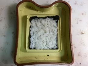 其中一张海苔放进模具里，盖上一层米饭