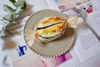 把米饭三明治从中间对半切开，包上硅油纸。