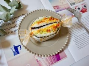 把米饭三明治从中间对半切开，包上硅油纸。