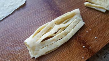 7．取一个切好的面胚展开，沿宽边对折。