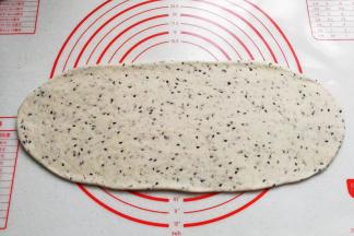 把醒好的面团擀成长舌状，稍微擀长擀薄些；