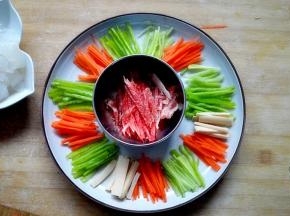 将青椒，胡萝卜，黄瓜，火腿肠切丝，摆盘，然后把肉切成细丝