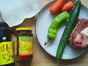 准备青椒20g 黄瓜一根 胡萝卜50g 肉100g 拉皮200g 豆瓣酱一勺 柚子酱油2勺 醋2勺 盐适量 火腿肠一根