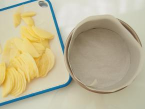 苹果切成均匀的厚度大概1mm左右的薄片，在模具底部和四周铺上油纸。