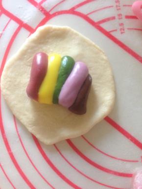 14、把松弛好的面团擀开 中间厚边缘薄  切大约25克彩虹麻薯内馅包入 收口捏紧 收圆 如果想拉出彩虹 摆放的时候 每一个都按照同样的方向摆