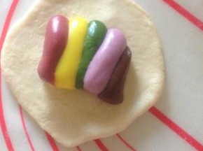 14、把松弛好的面团擀开 中间厚边缘薄  切大约25克彩虹麻薯内馅包入 收口捏紧 收圆 如果想拉出彩虹 摆放的时候 每一个都按照同样的方向摆