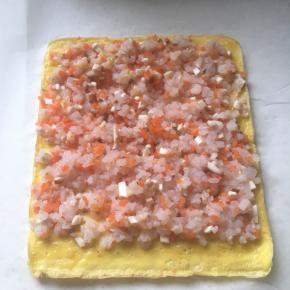 取出蛋皮，铺上搅拌好的虾仁馅，下面留一厘米的空