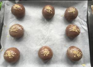 收口朝下放烤盘，刷蛋黄液，撒白芝麻