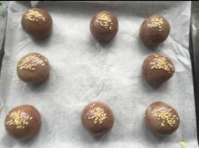 收口朝下放烤盘，刷蛋黄液，撒白芝麻