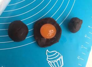 豆沙分成8个团，擀开包住蛋黄。