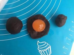 豆沙分成8个团，擀开包住蛋黄。