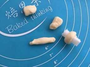 一边的10克面团分成4个，搓成条，围在油纸卷成的条柱上。