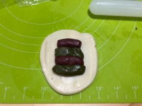 将水油皮擀开，中间部位放入两份红油酥、两份抹茶油酥，交叉放置