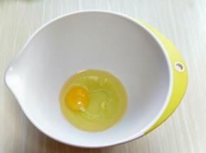 将鸡蛋和玉米油倒入容器中，用手动打蛋器抽打均匀。