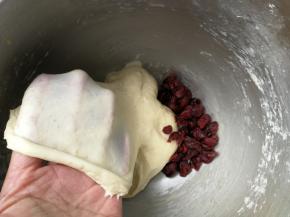 约6分钟后，面团能拉出结实不易破的膜，加入蔓越梅干，再次启动厨师机和面1分钟，把蔓越梅干均匀揉进面团即可