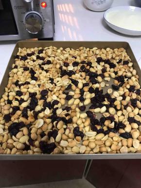 烤好的花生米放微凉，用手搓一下，花生皮很容易脱落的，然后对着水池用嘴巴吹一下，花生仁就干干净净的了，准备好的花生仁跟蔓越莓放烤箱里面低温备用，我开的70度火备用的，如果花生仁太凉，牛轧糖成品后，花生仁容易脱落下来，所以一定要保存余温