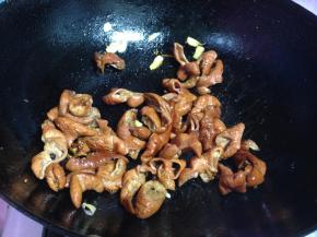 另起锅，加少量油下入蒜瓣和肥肠翻炒，用老抽调色