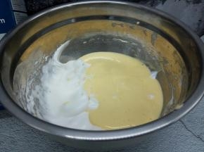 将拌匀的面糊倒入剩余的蛋白里，再次翻拌均匀即成戚风蛋糕面糊。倒入模具，振出大气泡