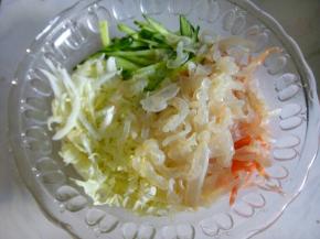 海蜇皮用烫水烫十几秒马上捞出控水，放进切好的菜里准备调味。